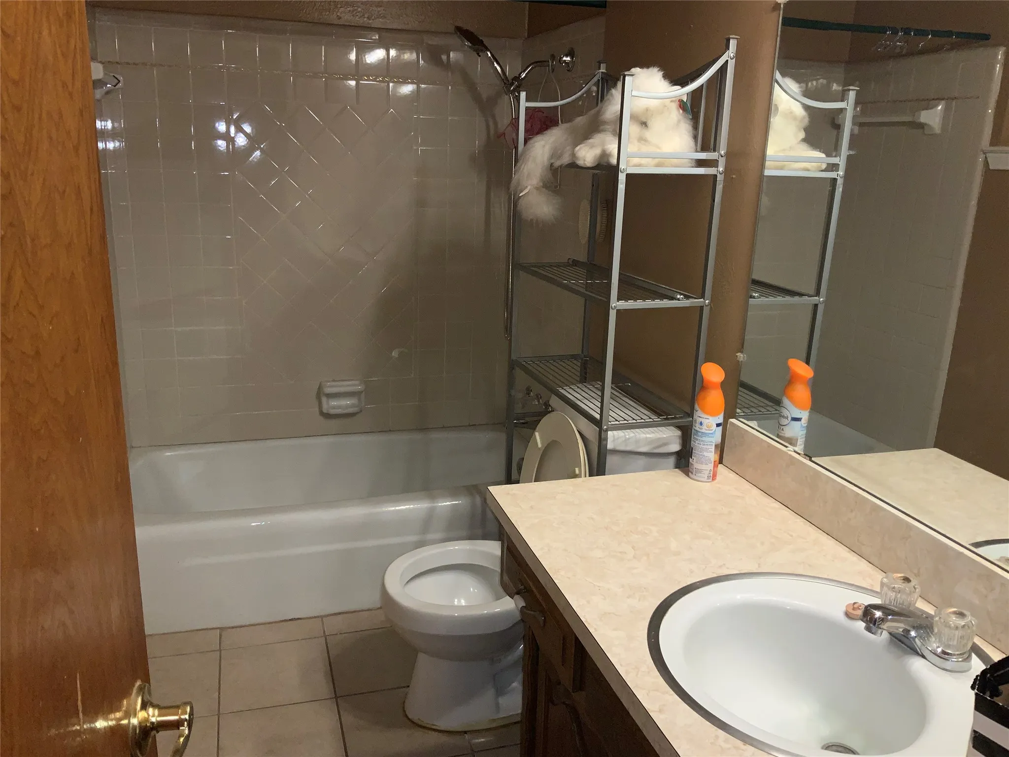 Bathroom featuring a shower/tub combination with tiled surround, a vanity with an integrated sink, a large wall-mounted mirror, and tile flooring