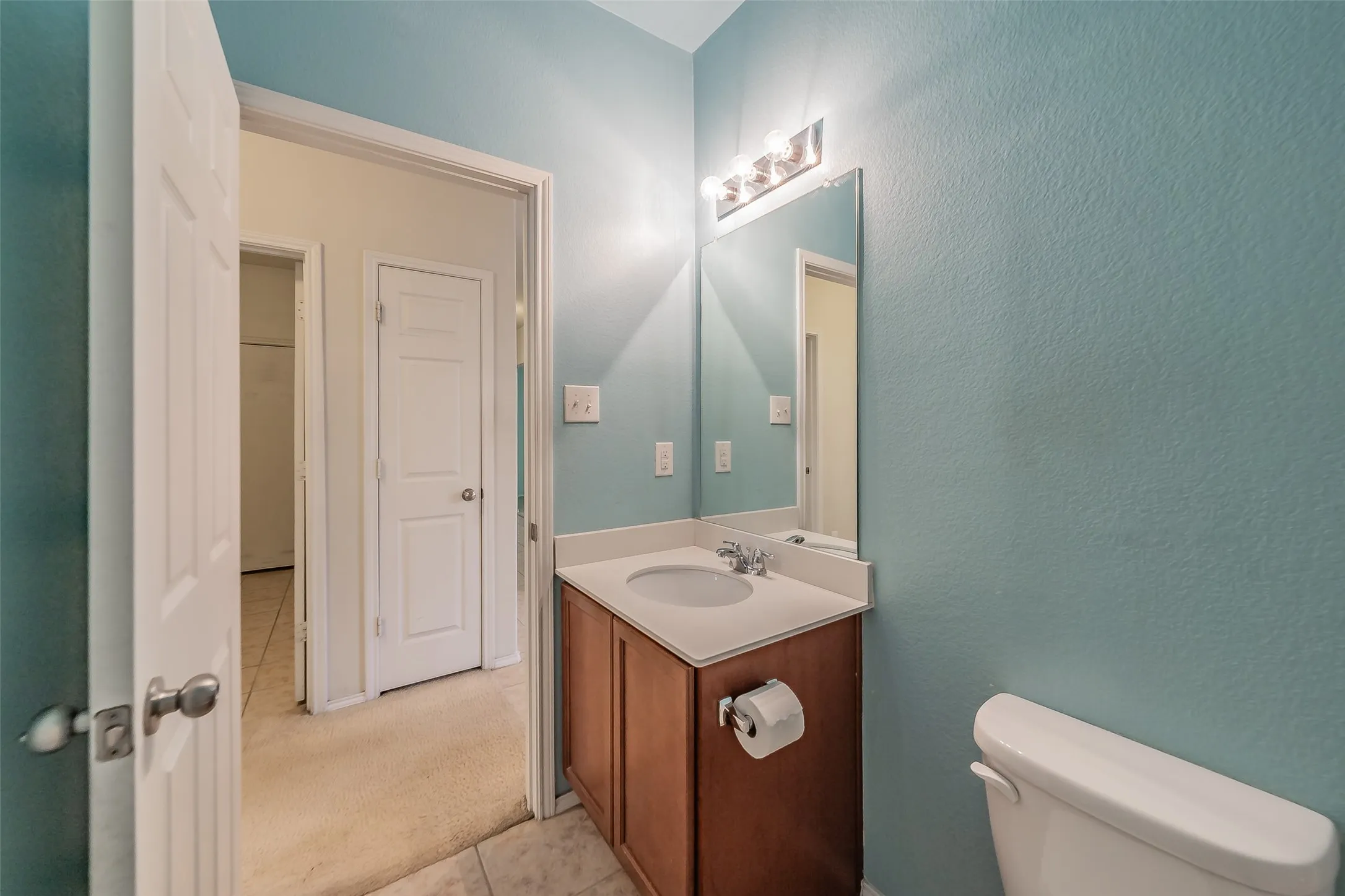 Bathroom featuring a single vanity with a wood-finish cabinet, light-toned countertop, and an integrated sink