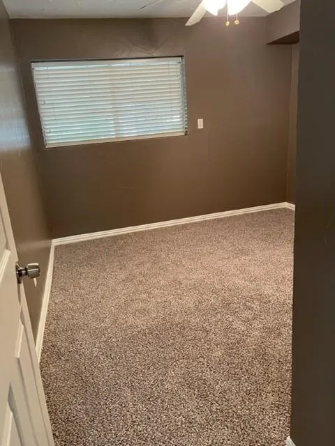 Textured carpeting, white baseboards, and a window with blinds