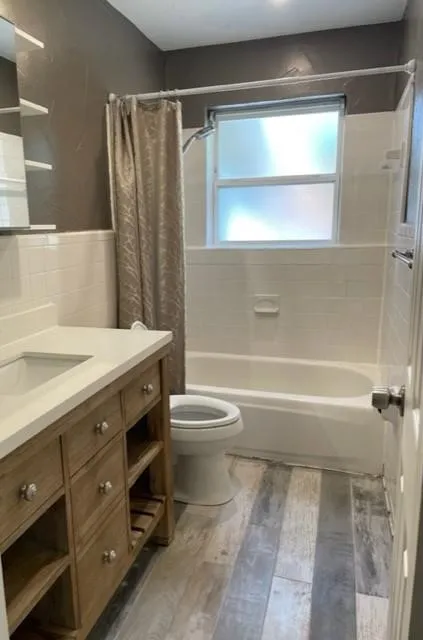 Wood-finish flooring with a white vanity featuring a rectangular sink and ample storage