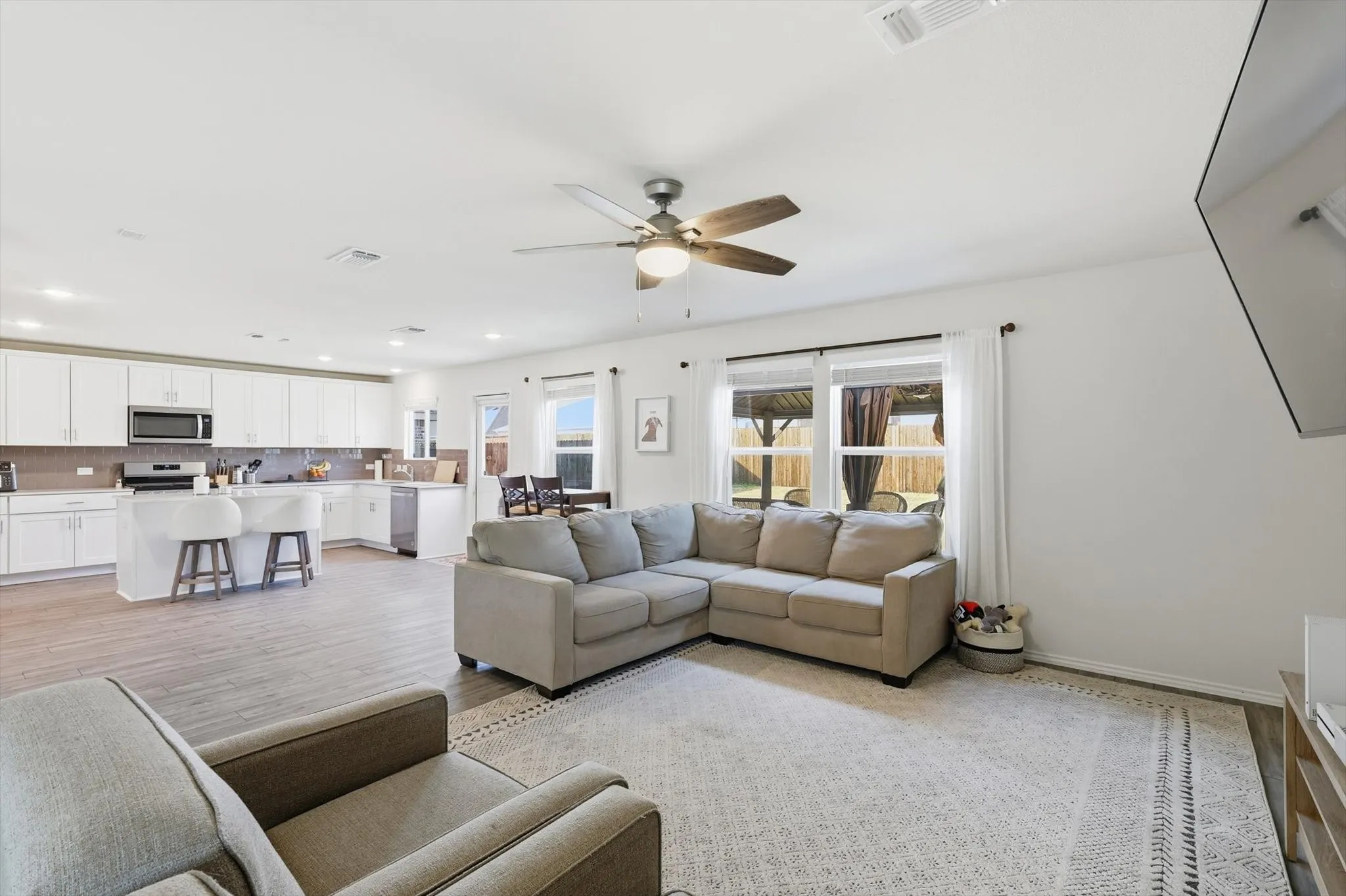 Living area with light wood finished floors, a ceiling fan, and recessed lighting