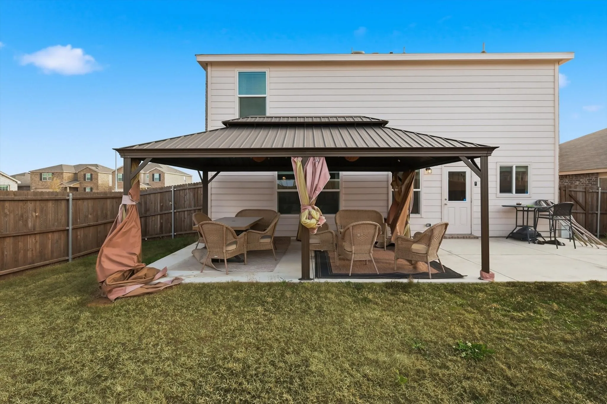 Back of property featuring a gazebo, a patio, a fenced backyard, a metal roof, and outdoor lounge area