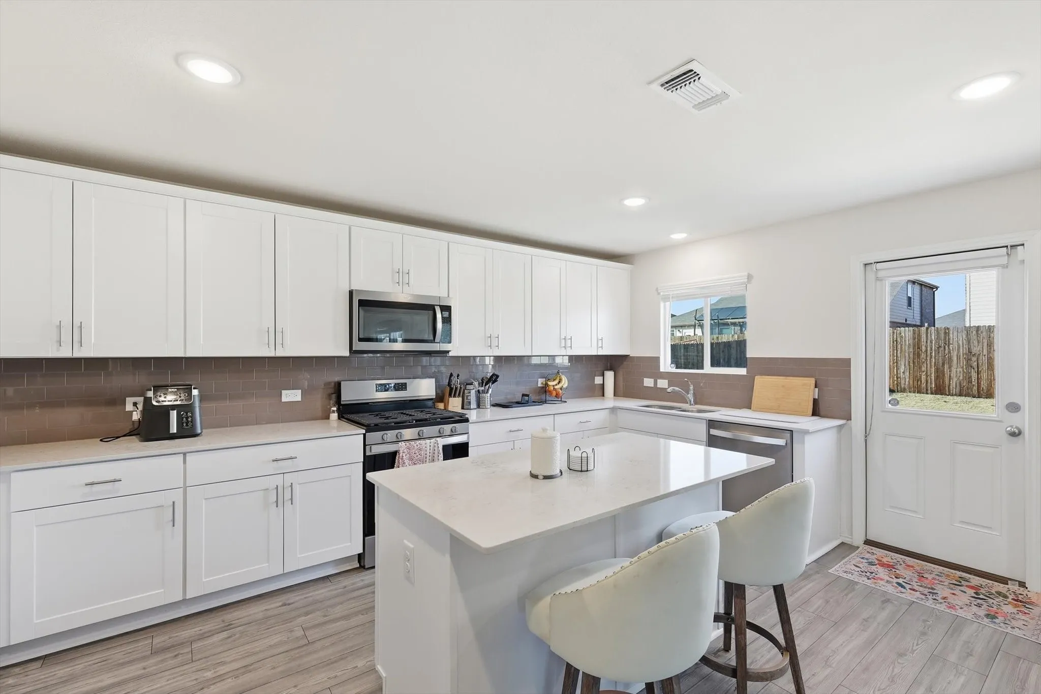Kitchen with appliances with stainless steel finishes, white cabinets, a kitchen bar, a kitchen island, and tasteful backsplash