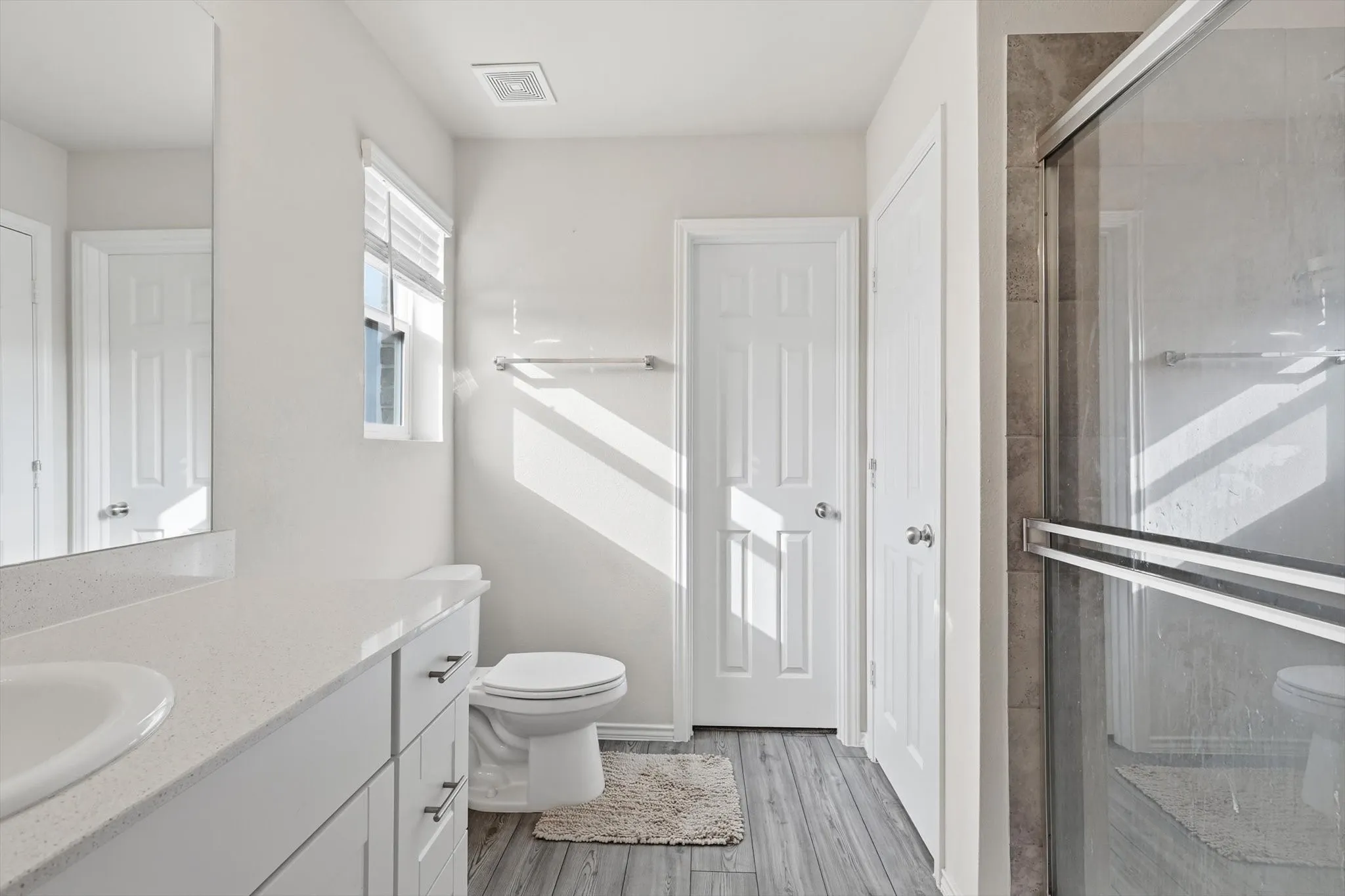 Full bath featuring vanity, a stall shower, and light wood finished floors