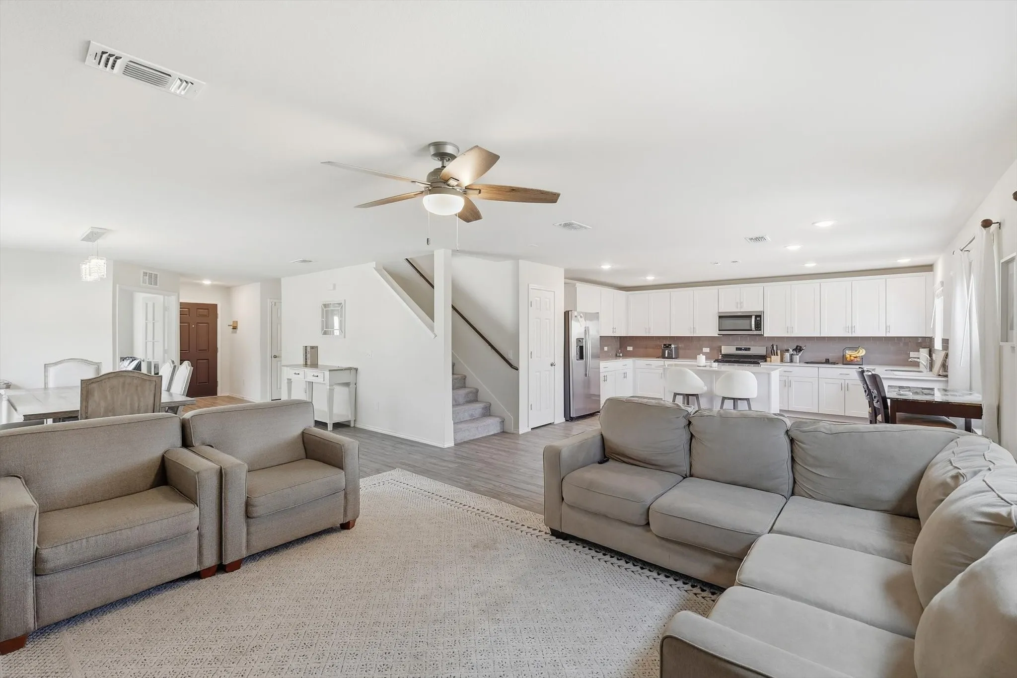 Living room featuring light wood-style flooring, a ceiling fan, stairs, and recessed lighting