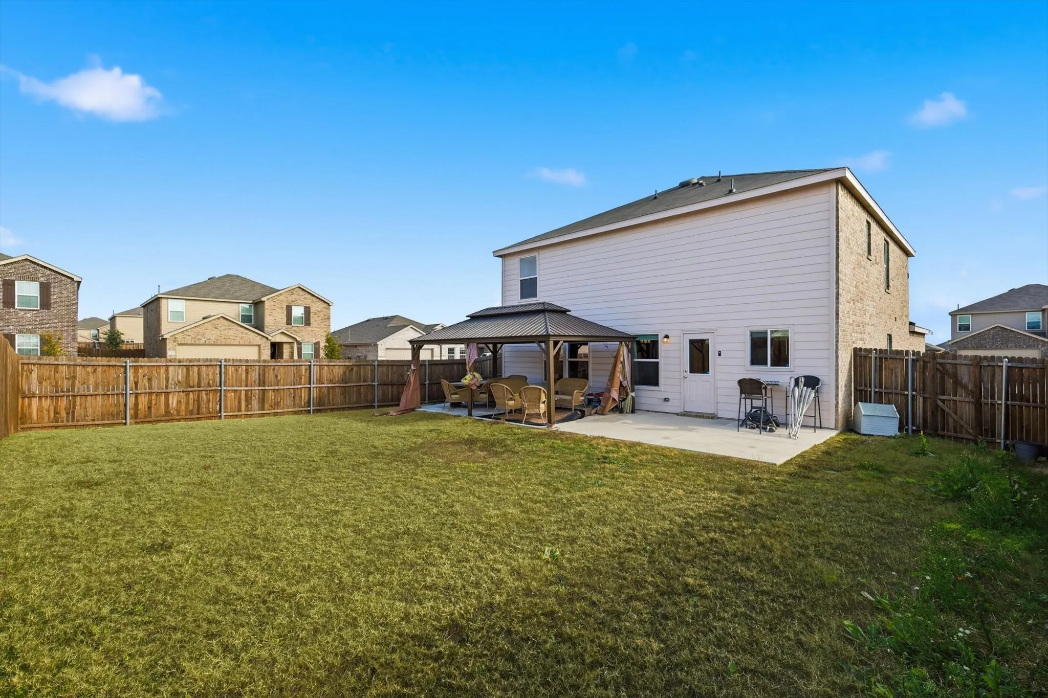 Back of property featuring a gazebo, a patio, and a fenced backyard
