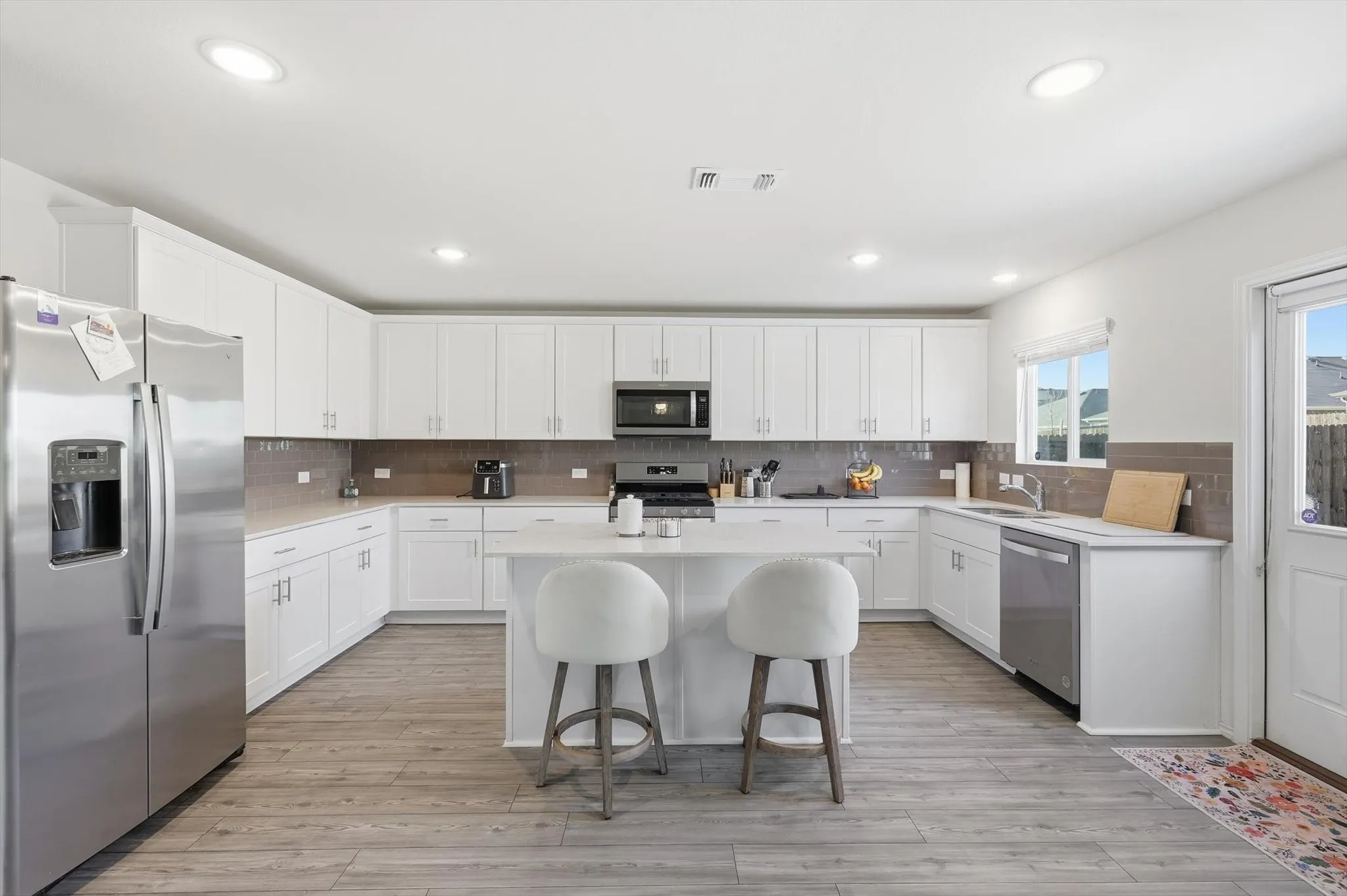 Kitchen with stainless steel appliances, a center island, a breakfast bar area, white cabinets, and backsplash