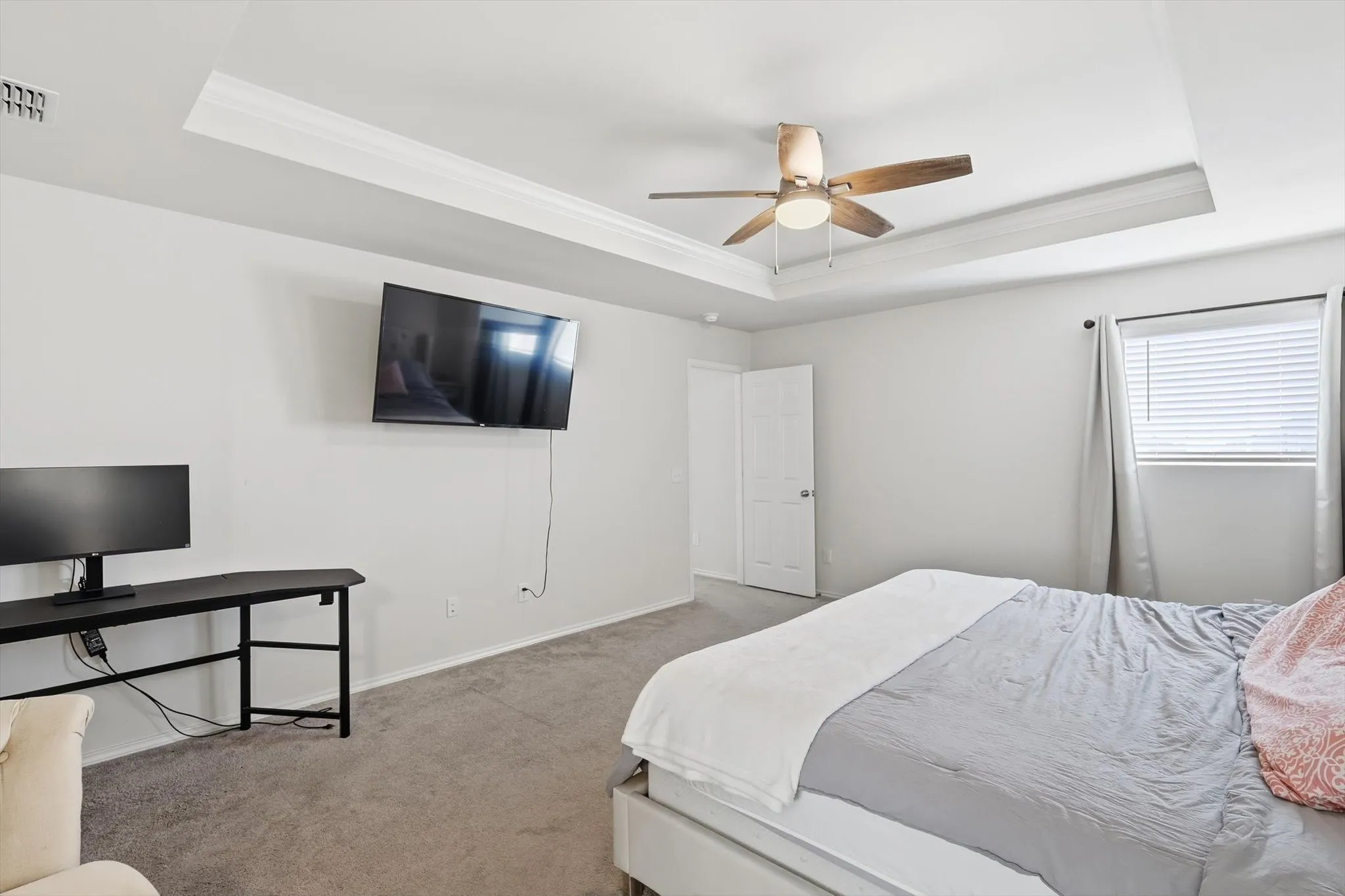 Bedroom with crown molding, a tray ceiling, carpet, and ceiling fan