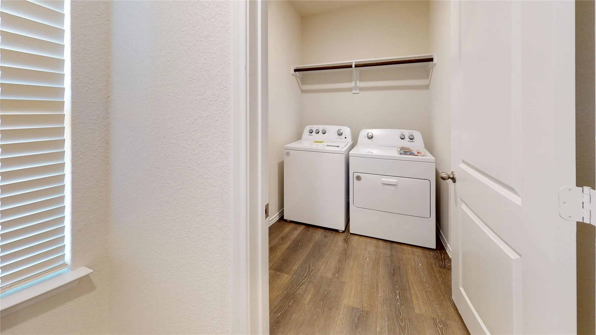 Laundry area featuring wood finished floors, washer and dryer, and a textured wall