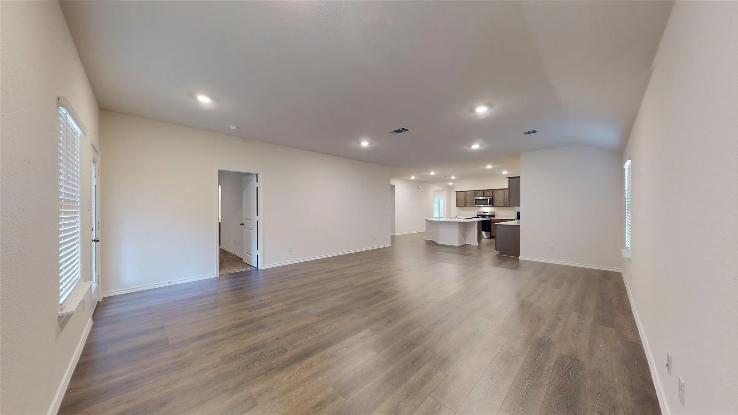 Unfurnished living room with healthy amount of natural light, dark wood-style flooring, and recessed lighting