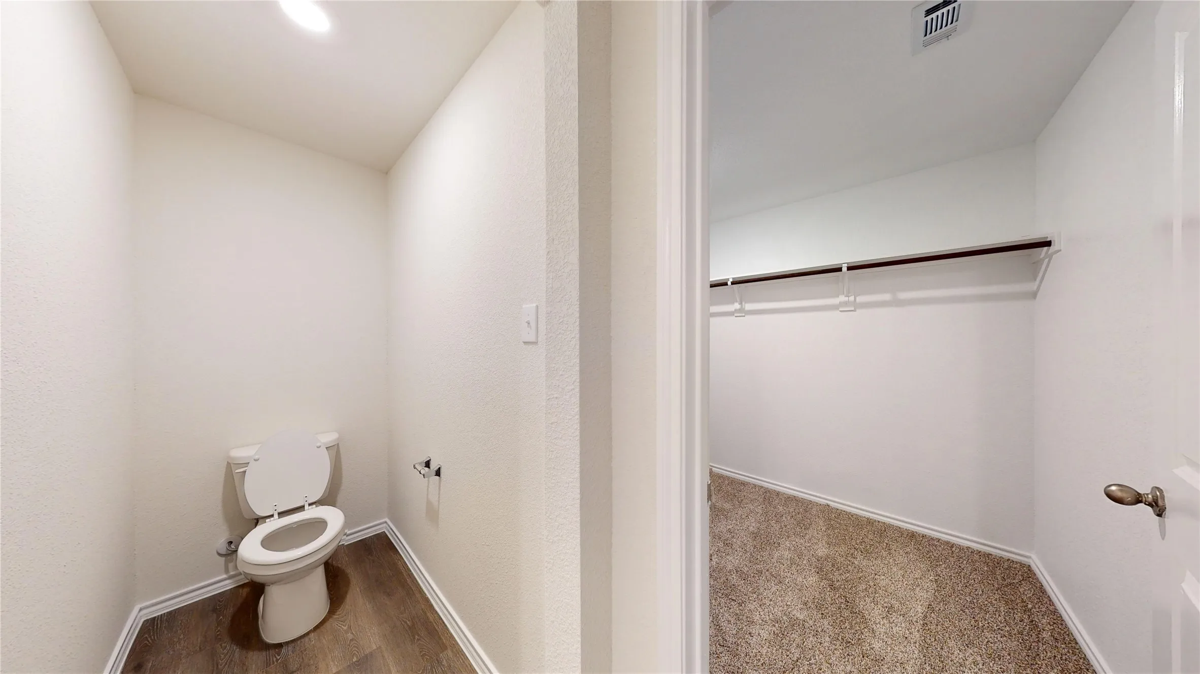 Bathroom featuring a spacious closet and dark colored carpet