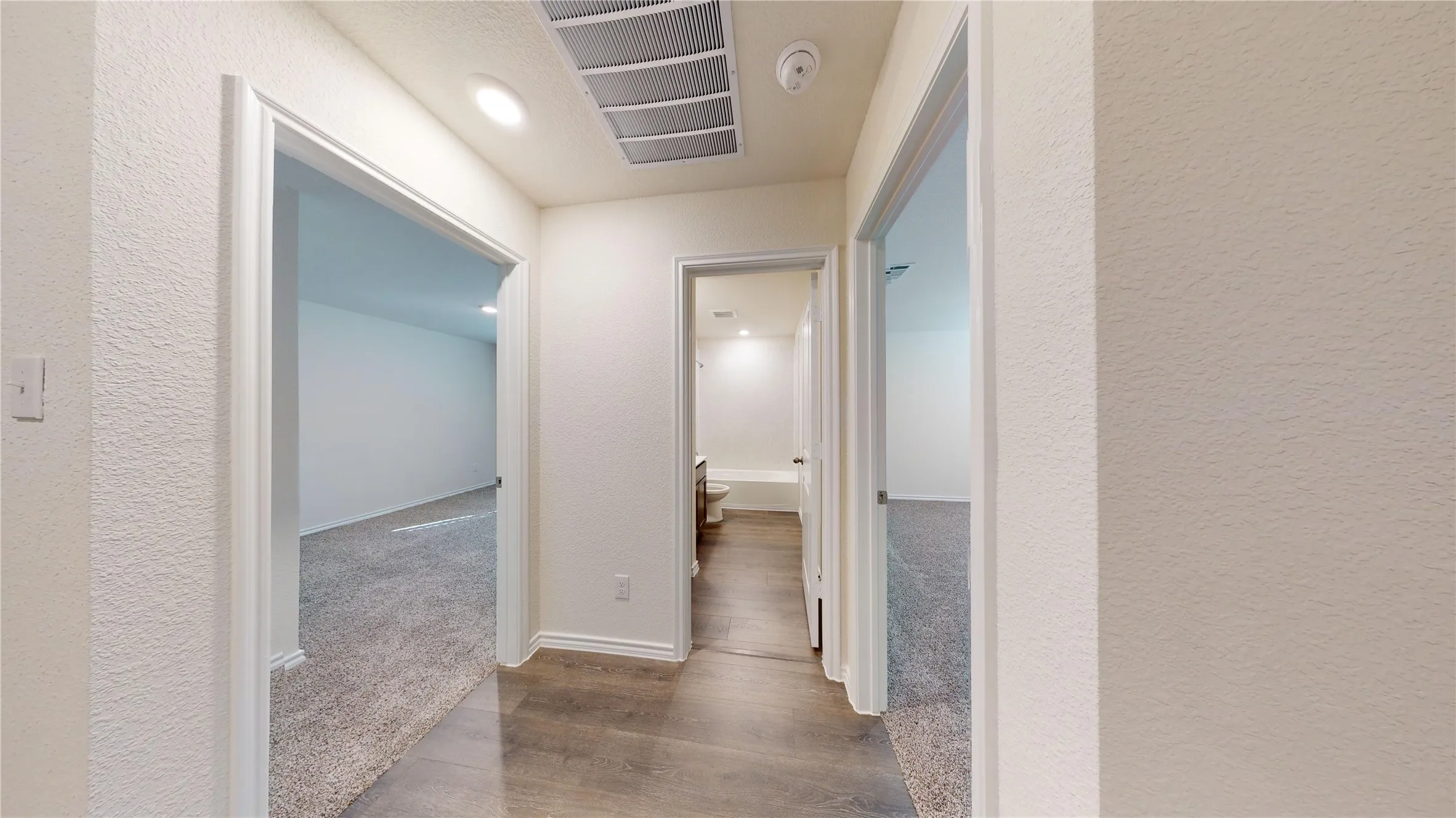 Corridor with a textured wall, dark wood-style floors, and recessed lighting