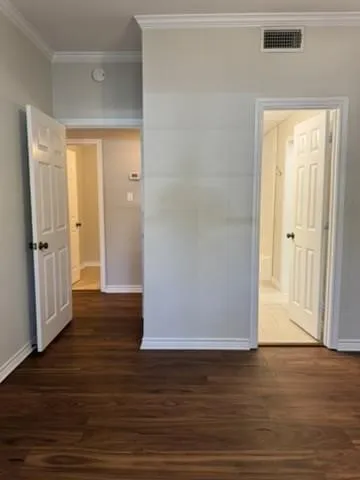 Hall with crown molding and dark wood-type flooring