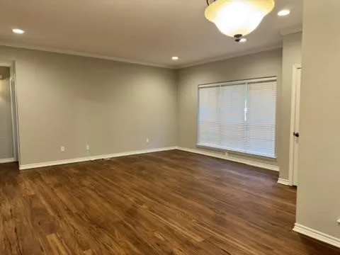 Empty room with dark wood-style flooring, recessed lighting, and ornamental molding