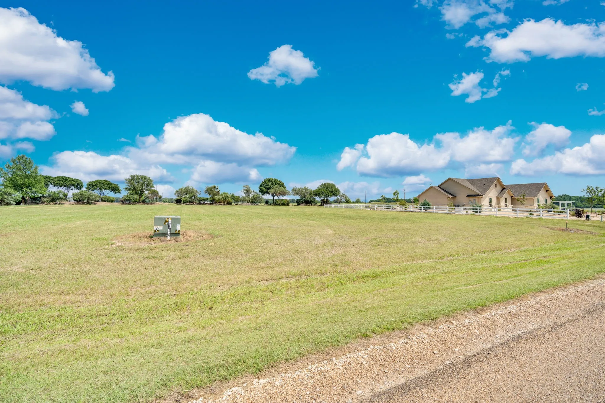 Expansive grass lawn with a light-colored fence bordering the property