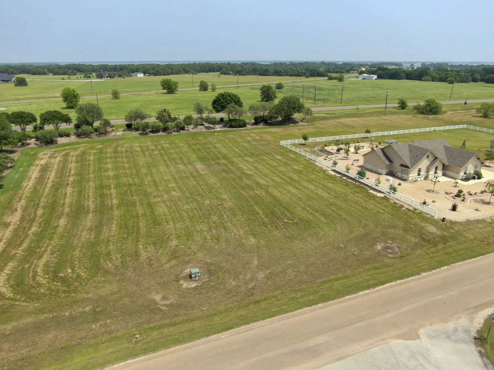 Expansive green lot featuring a rural setting and distant tree line