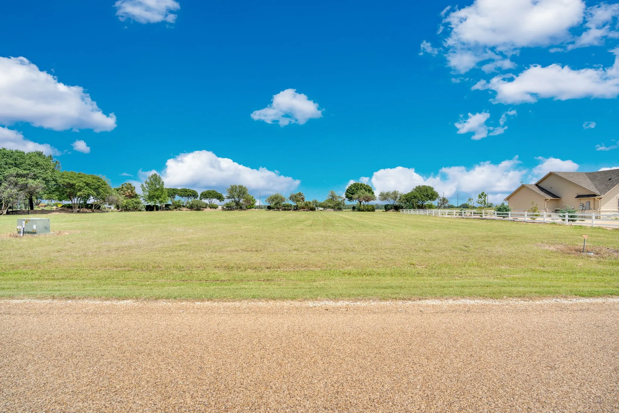 Expansive green landscape with a white fence bordering the property