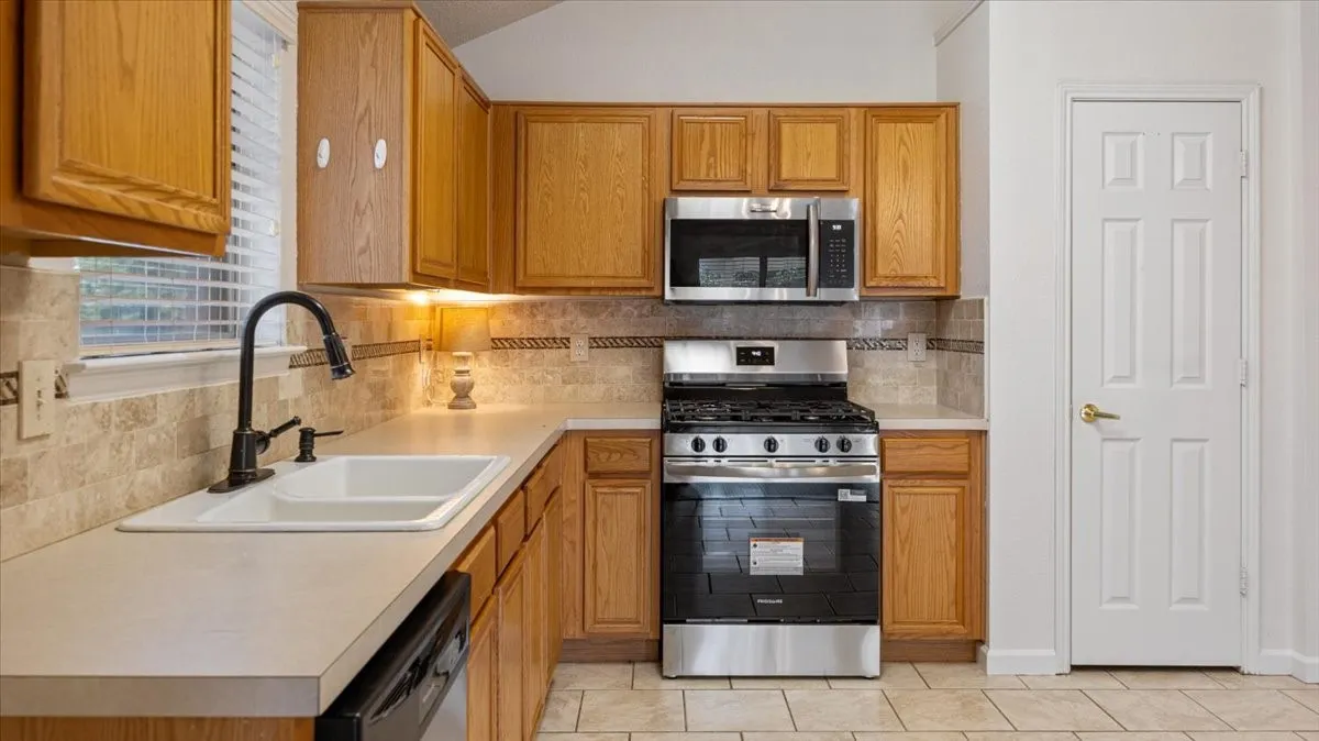Kitchen featuring wood cabinetry, white countertops, tile flooring, and a stainless steel oven/range with an overhead microwave