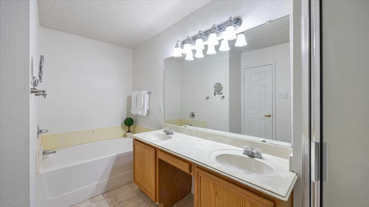 Primary bathroom with double vanity, dual sinks, and a large garden tub.