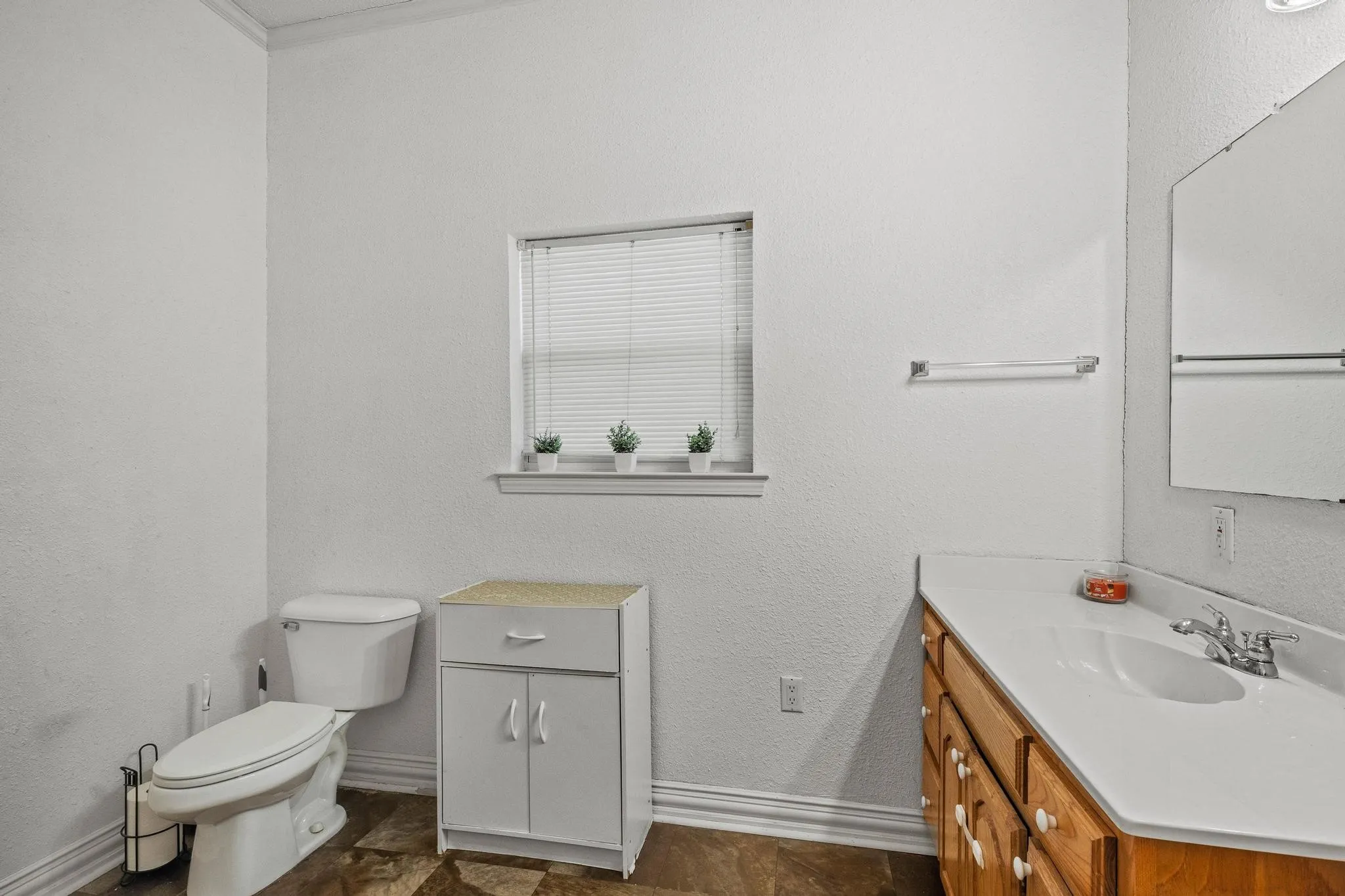 Full bath with toilet, single vanity and shower serves guests and the secondary bedrooms