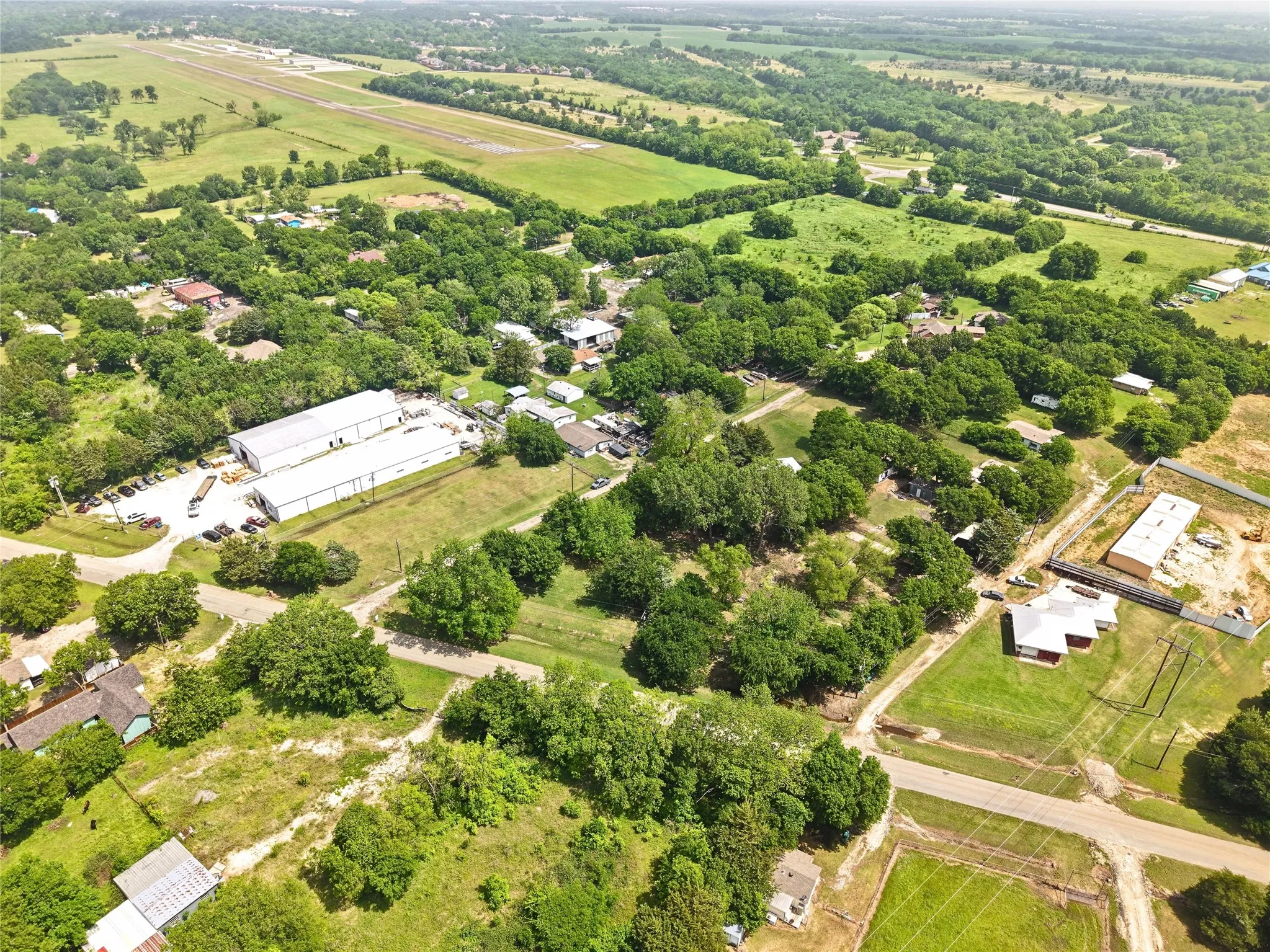 Aerial perspective showcasing a sprawling landscape with abundant mature trees and verdant fields