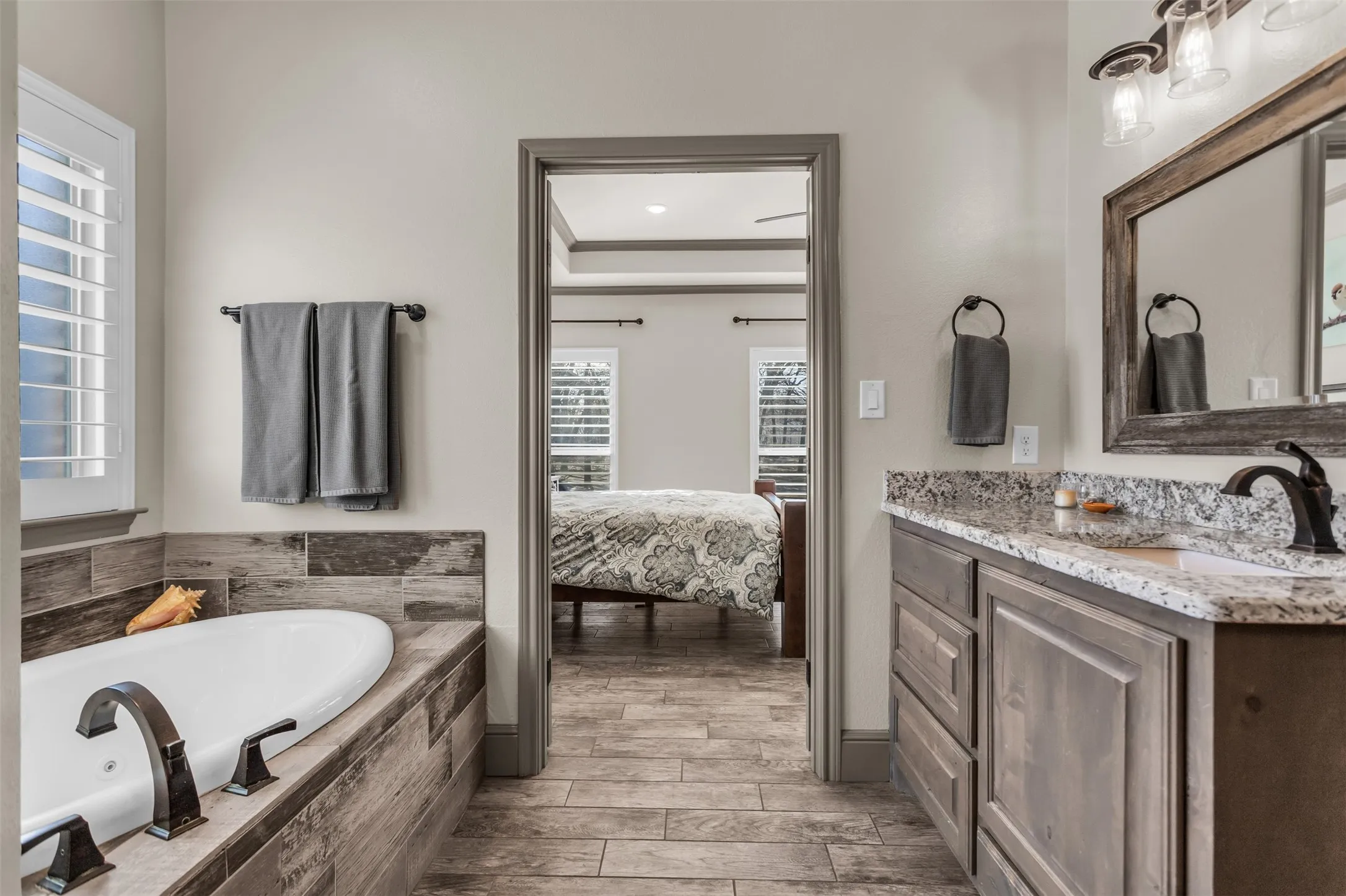 Full bathroom with vanity, a bath, wood finish floors, connected bathroom, and recessed lighting