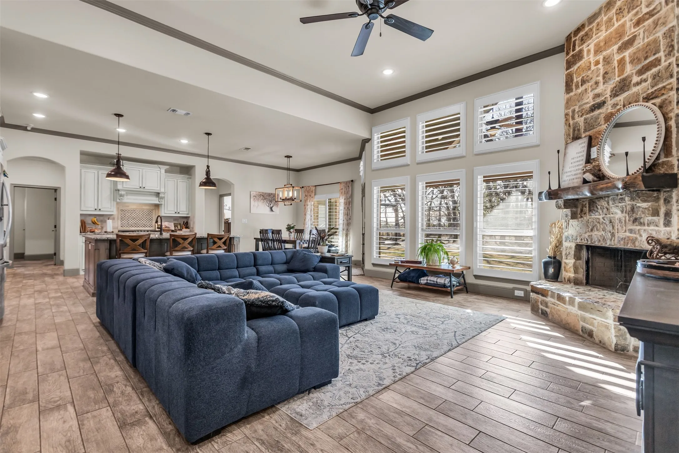 Living room featuring crown molding, light wood-style flooring, arched walkways, a fireplace, and recessed lighting