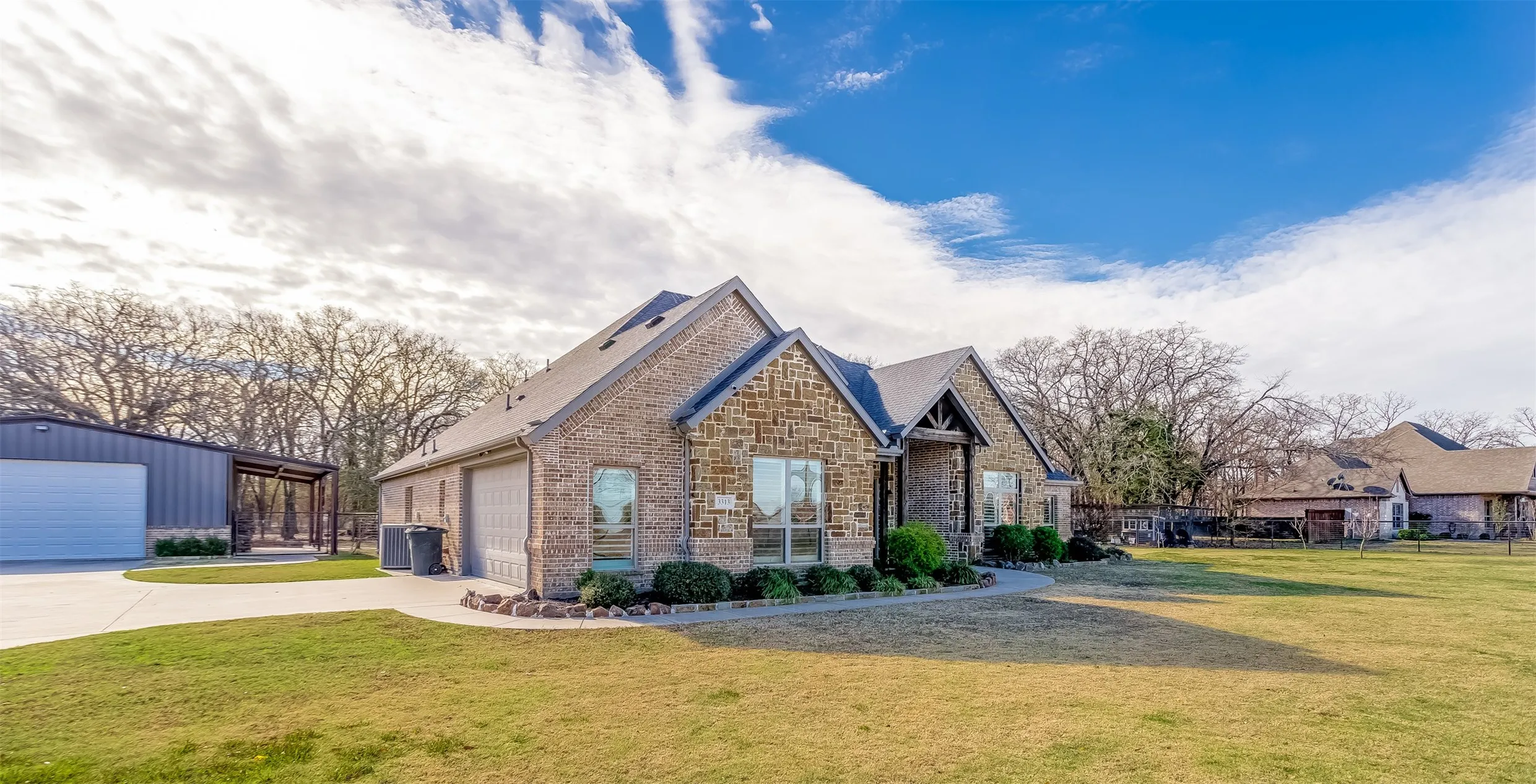 View of front of home with a front yard, a garage, brick siding, and stone siding