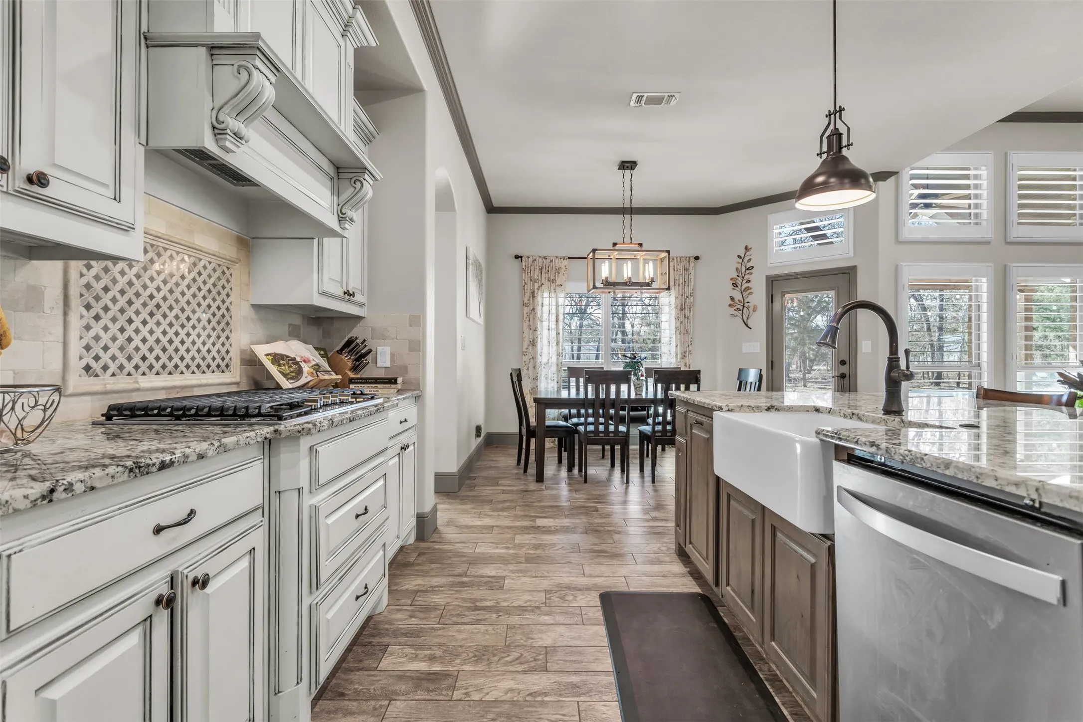 Kitchen featuring light stone countertops, ornamental molding, appliances with stainless steel finishes, decorative light fixtures, and wood tiled floors