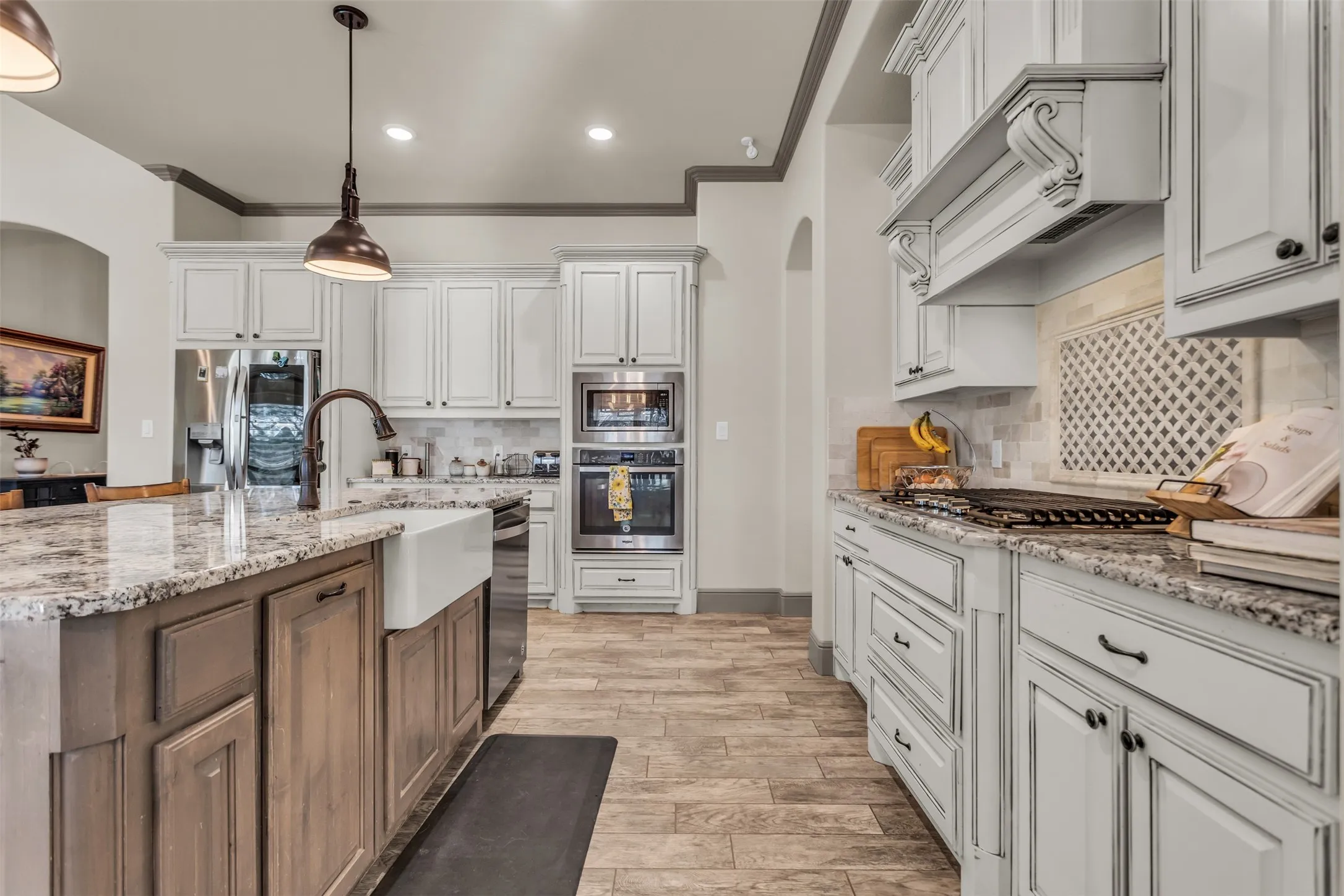 Kitchen with light stone countertops, white cabinetry, arched walkways, stainless steel appliances, and ornamental molding