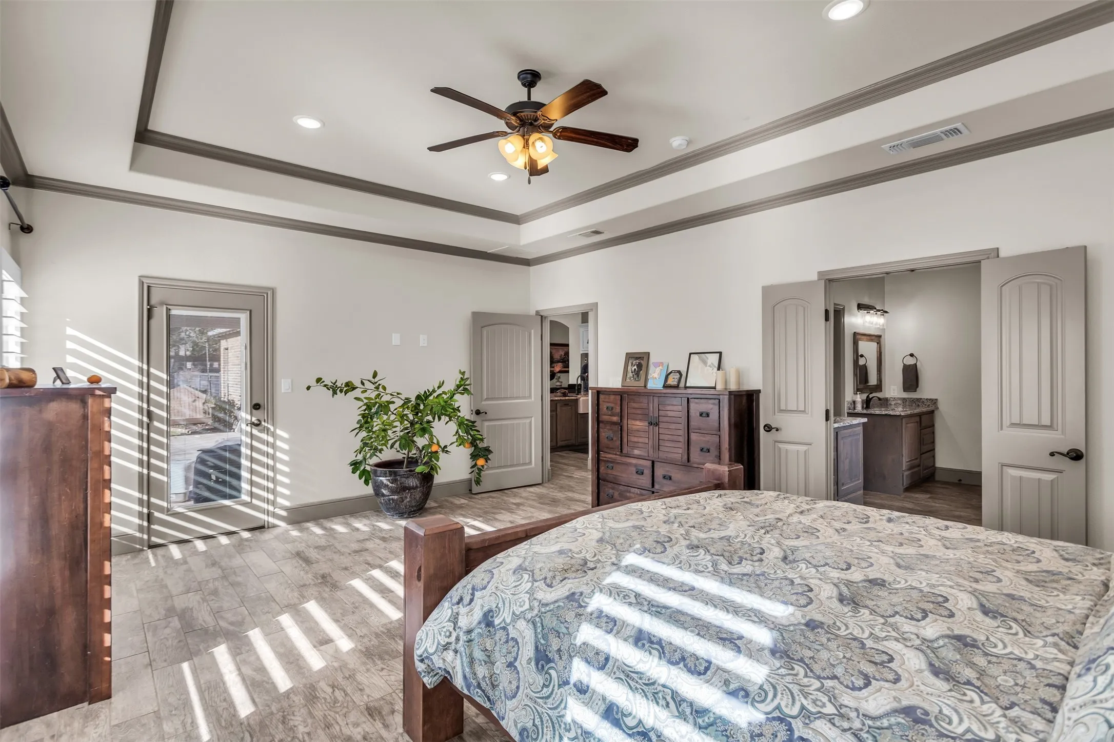 Bedroom featuring wood finished floors, ornamental molding, ceiling fan, recessed lighting, and a raised ceiling