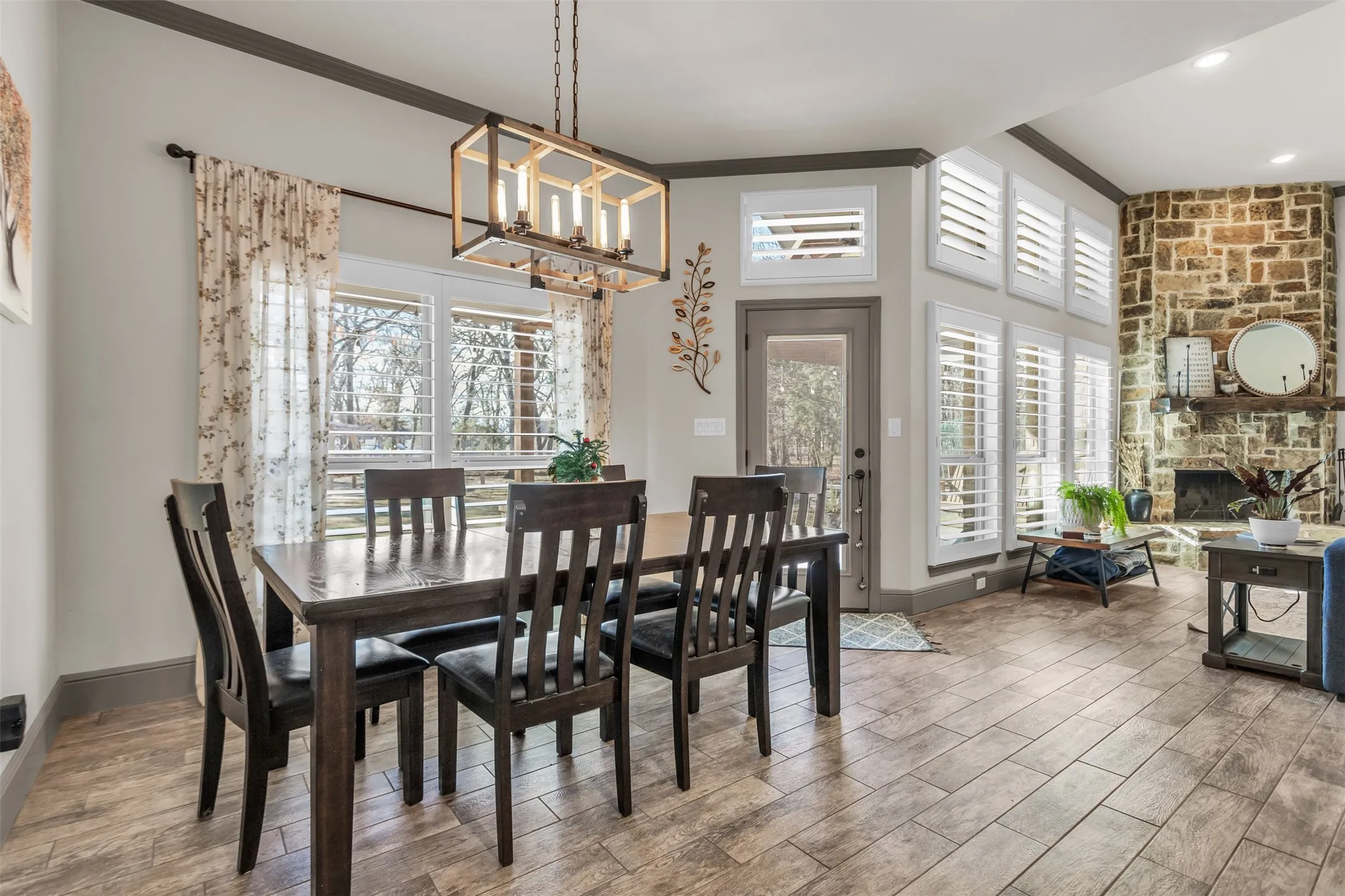 Dining area featuring crown molding, a fireplace, wood tiled floors, and a chandelier