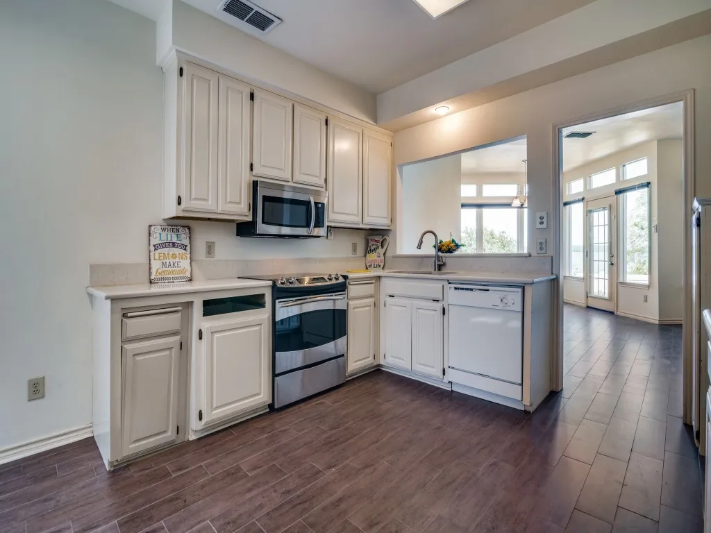 Kitchen featuring appliances with stainless steel finishes, dark wood finished floors, and light countertops