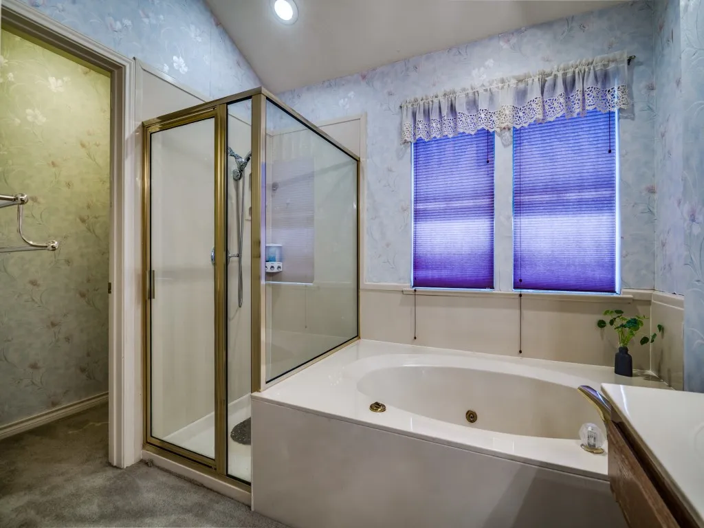 Bathroom featuring wallpapered walls, a stall shower, a tub with jets, and vanity