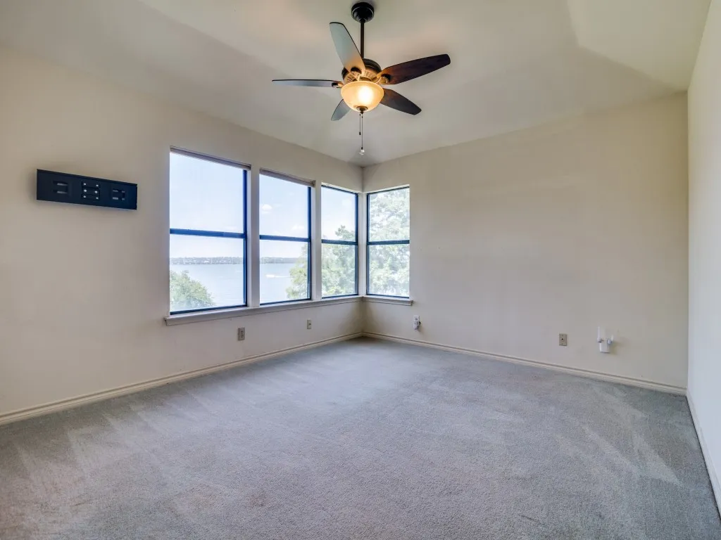 Spare room with a ceiling fan, carpet floors, and a water view