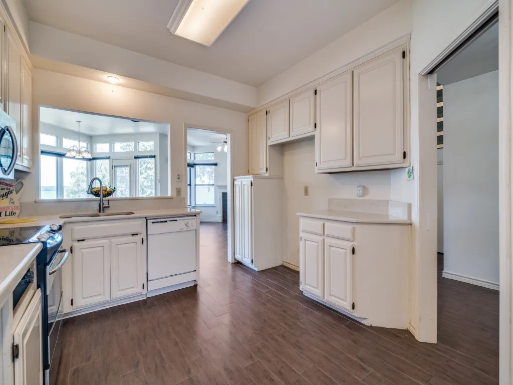 Kitchen with light countertops, stainless steel appliances, dark wood finished floors, a chandelier, and white cabinets