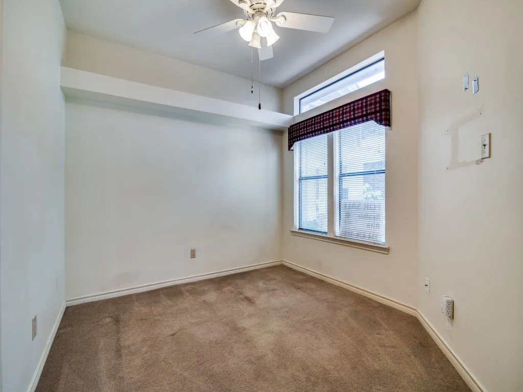 Carpeted empty room with a ceiling fan and baseboards