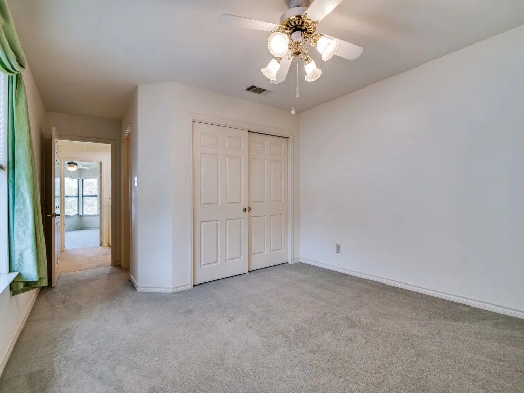 Unfurnished bedroom featuring light colored carpet, a closet, and a ceiling fan