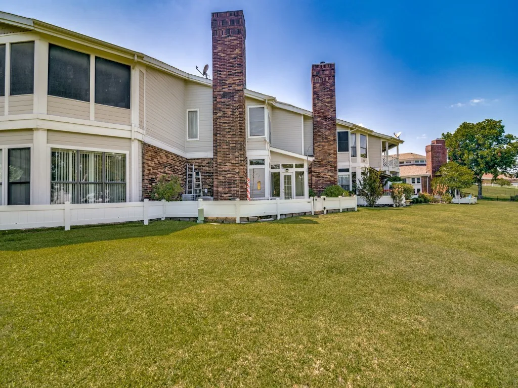 Back of property featuring a chimney and a lawn