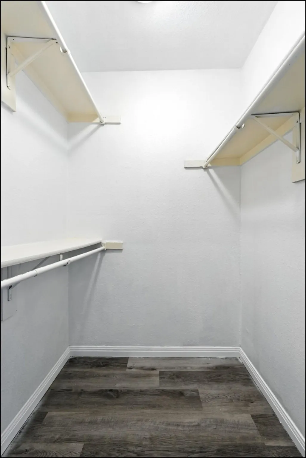 Spacious closet with dark wood-style floors