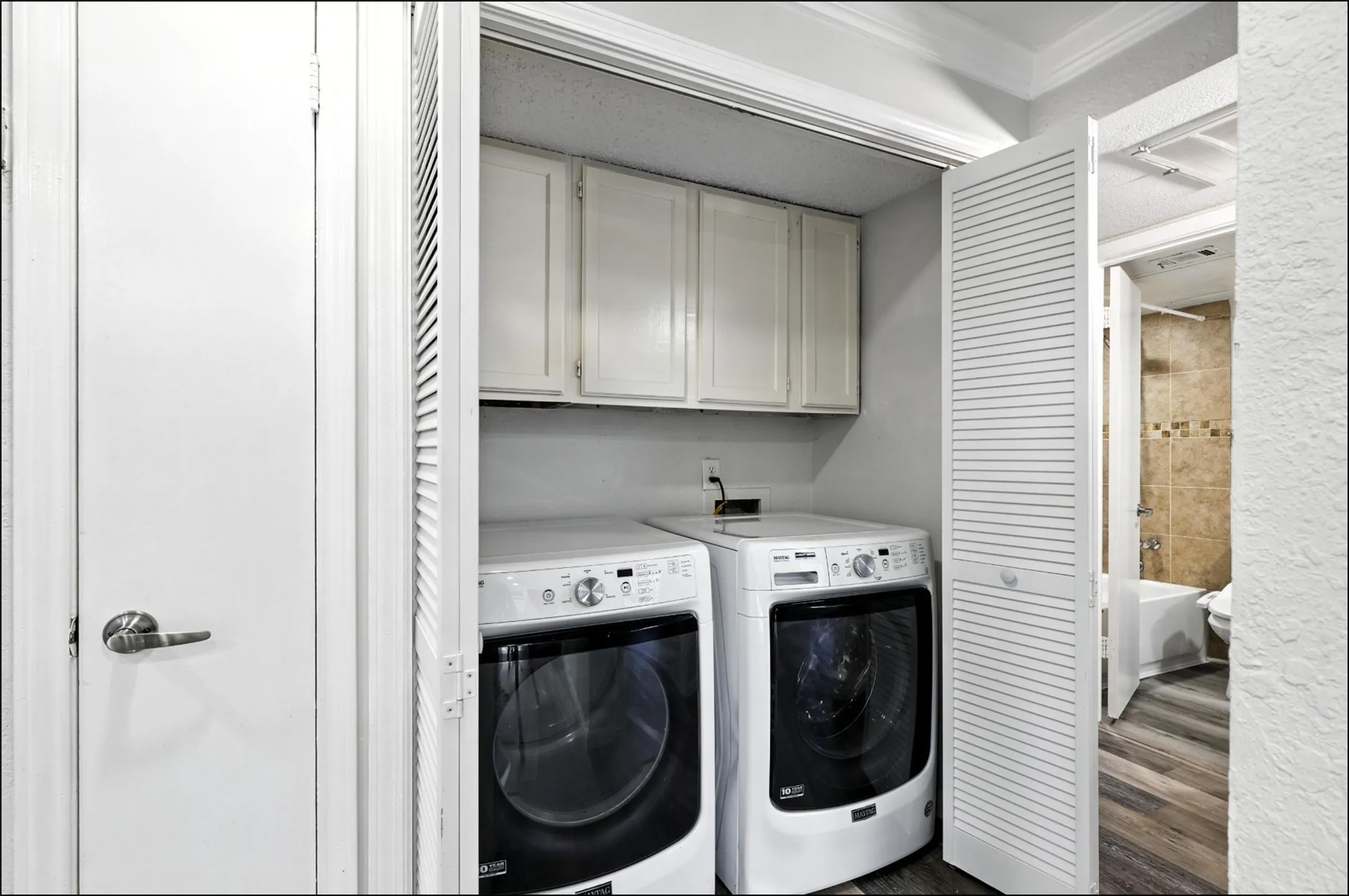 Laundry room featuring cabinet space, washer and clothes dryer, crown molding, and dark wood-style floors