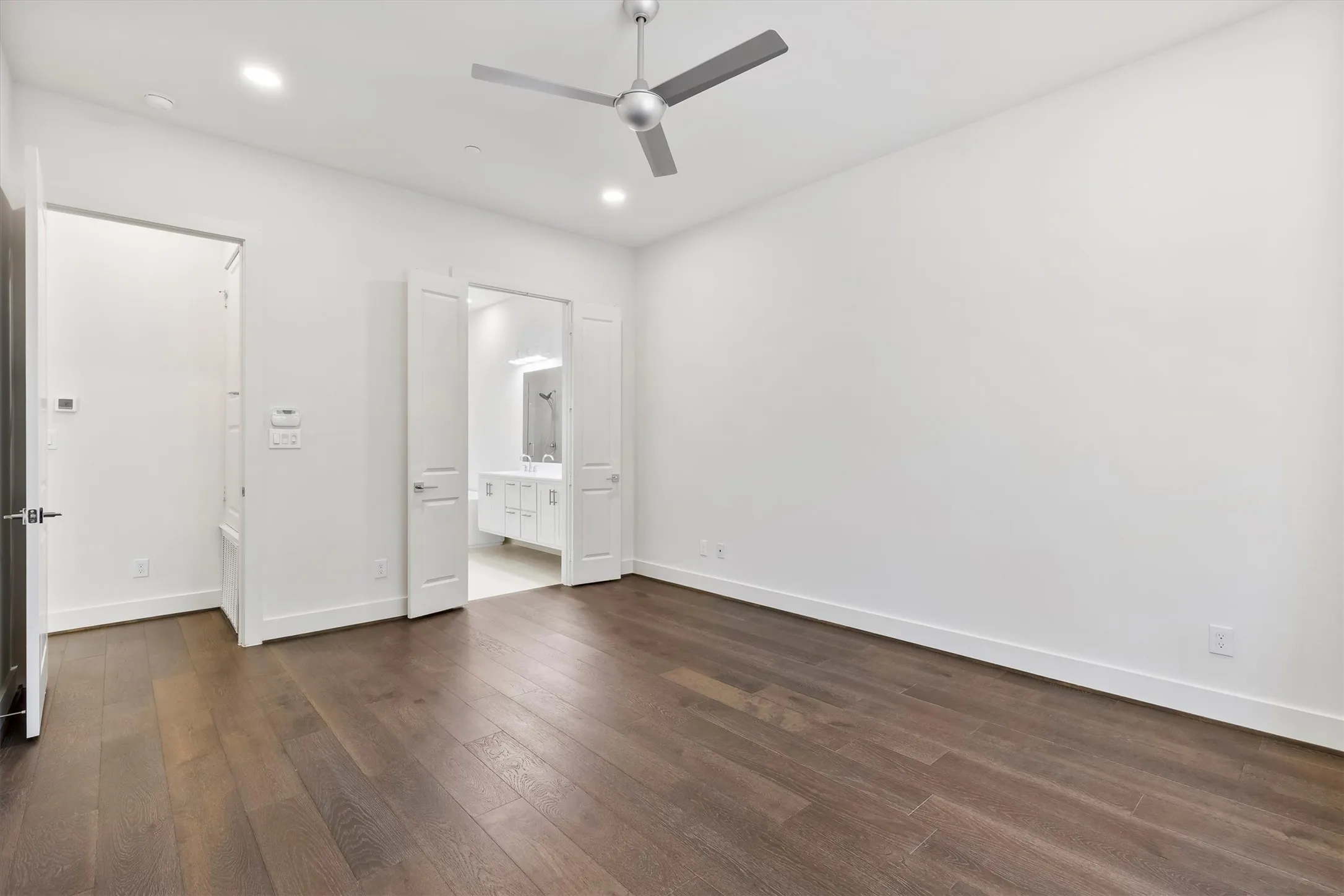 Unfurnished bedroom featuring dark wood floors, a ceiling fan, ensuite bathroom, and recessed lighting