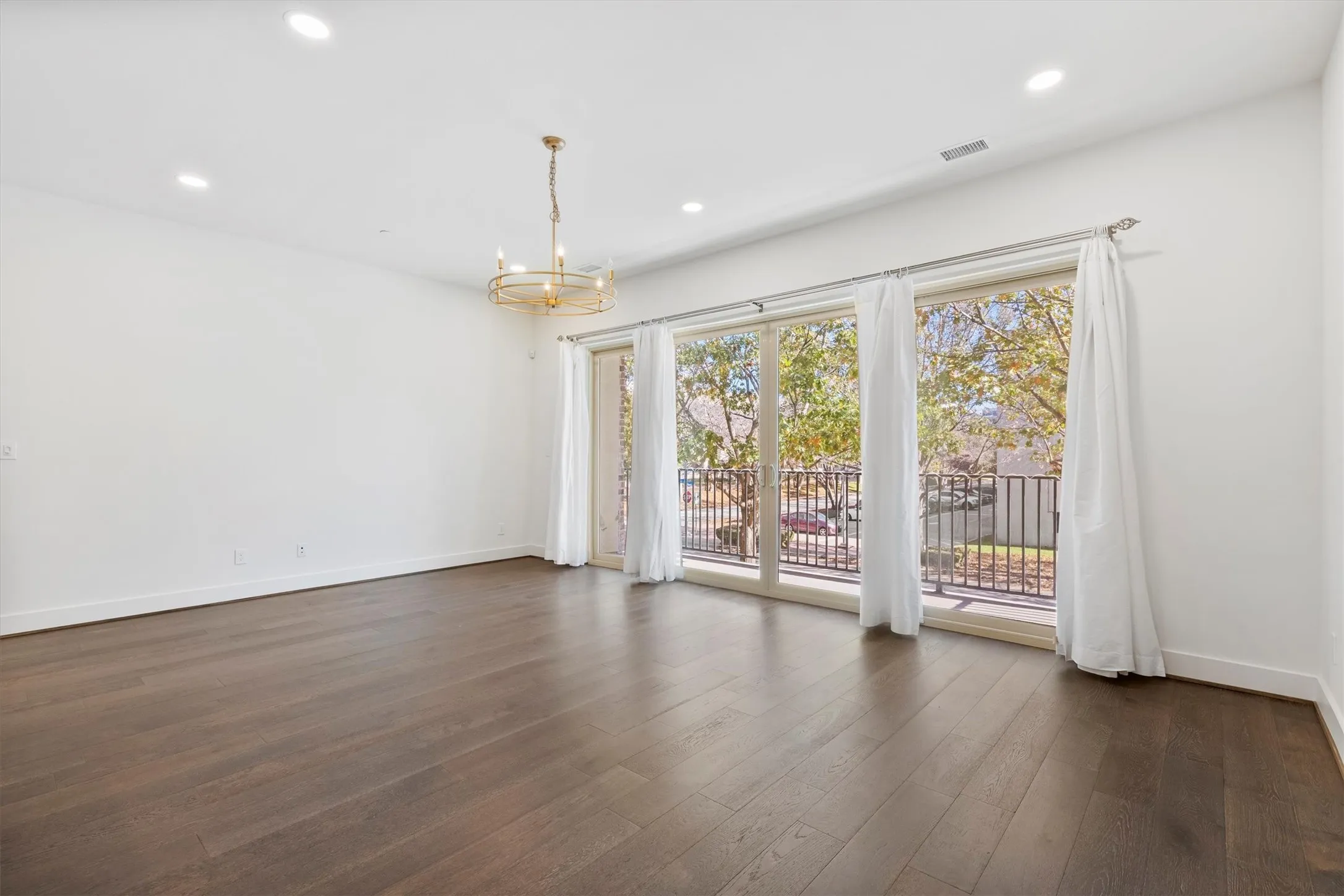 Empty room featuring a chandelier, dark wood flooring, and recessed lighting