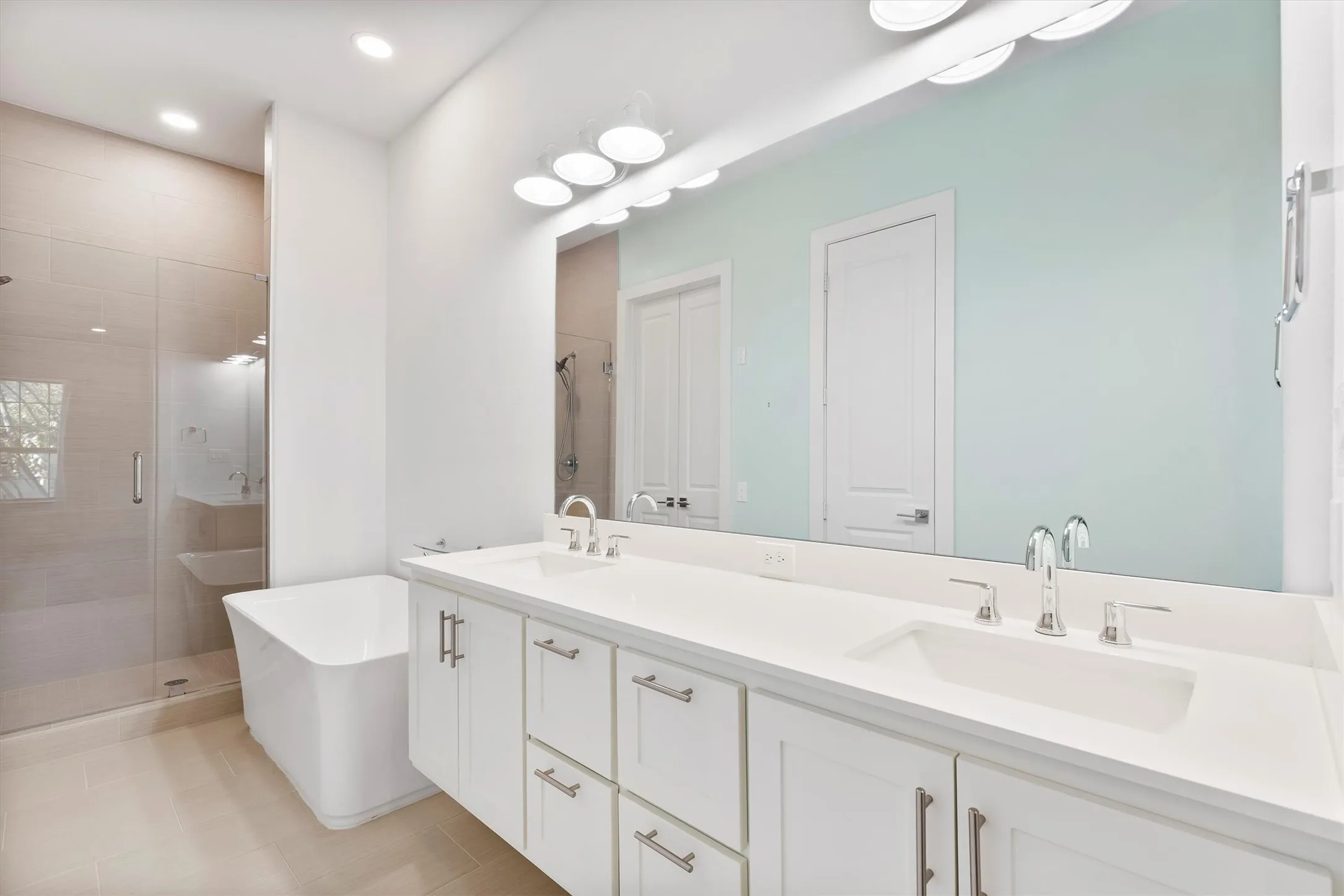 Bathroom with double vanity, a shower stall, a freestanding bath, and recessed lighting