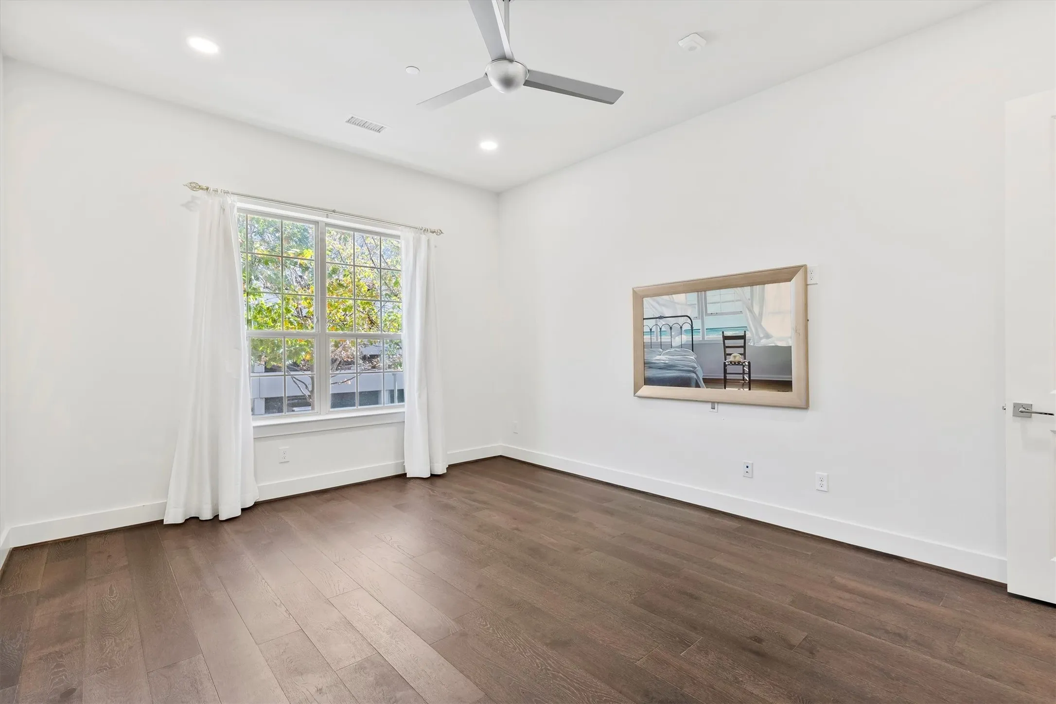Empty room featuring dark wood flooring, a ceiling fan, and recessed lighting