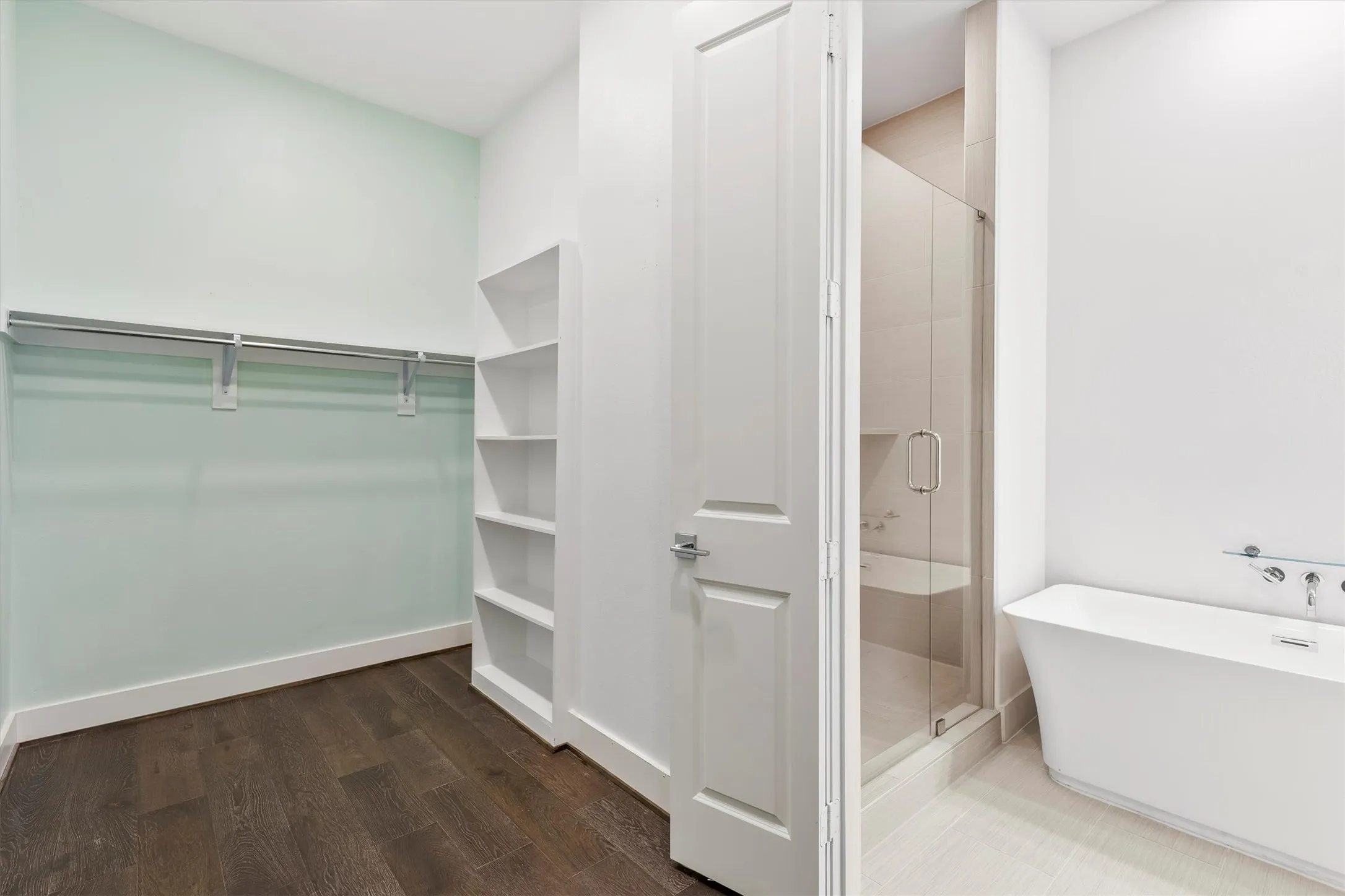 Spacious closet in primary bedroom with dark wood flooring