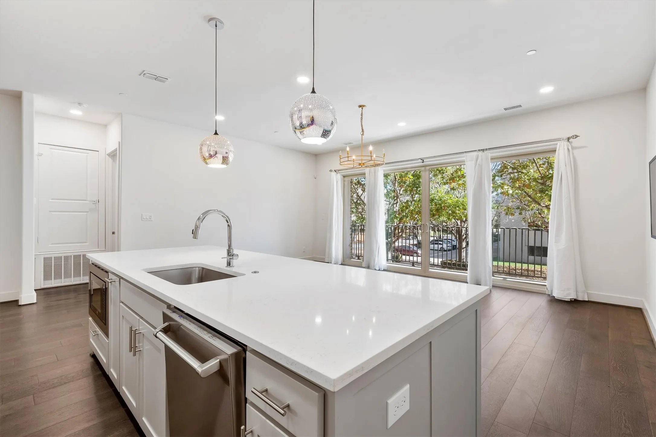 Kitchen with stainless steel appliances, dark wood flooring, pendant lighting, light stone counters, and recessed lighting