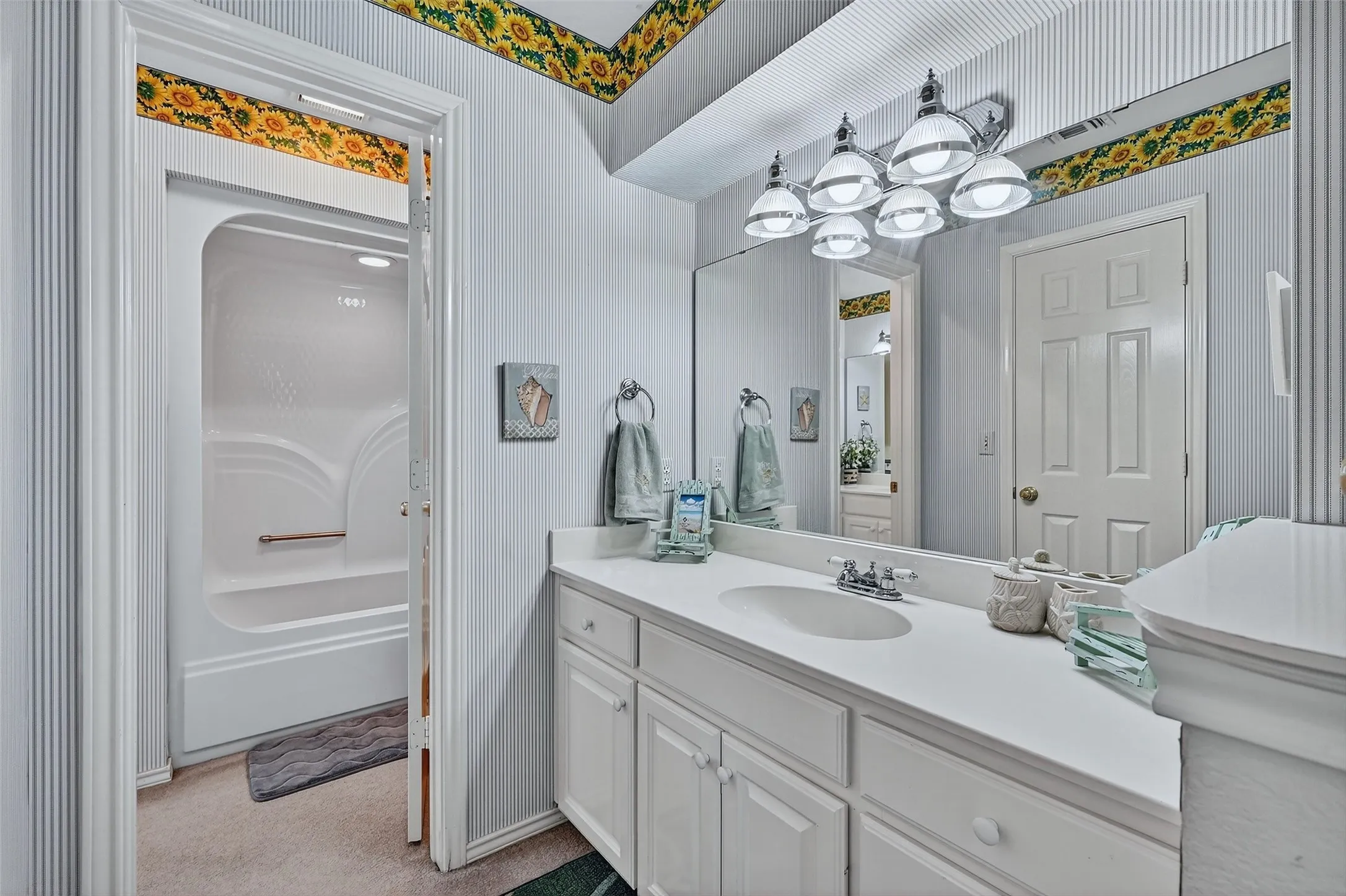 Bathroom with vanity, wallpapered walls, and a chandelier