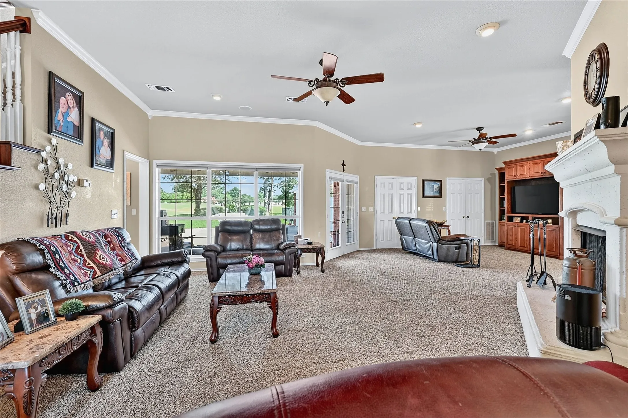 Living room with ceiling fan, light colored carpet, crown molding, recessed lighting, and a fireplace with raised hearth