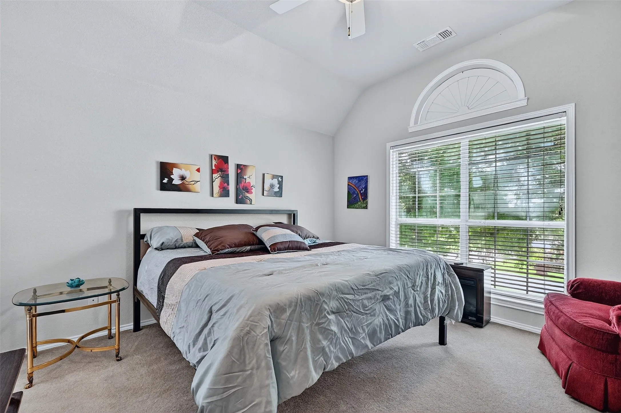 Carpeted bedroom with vaulted ceiling and a ceiling fan